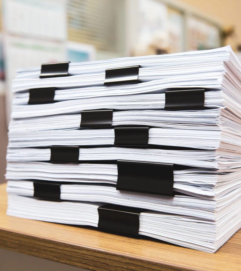 Pile of a lots paperwork report or printout document on desk office stack up.